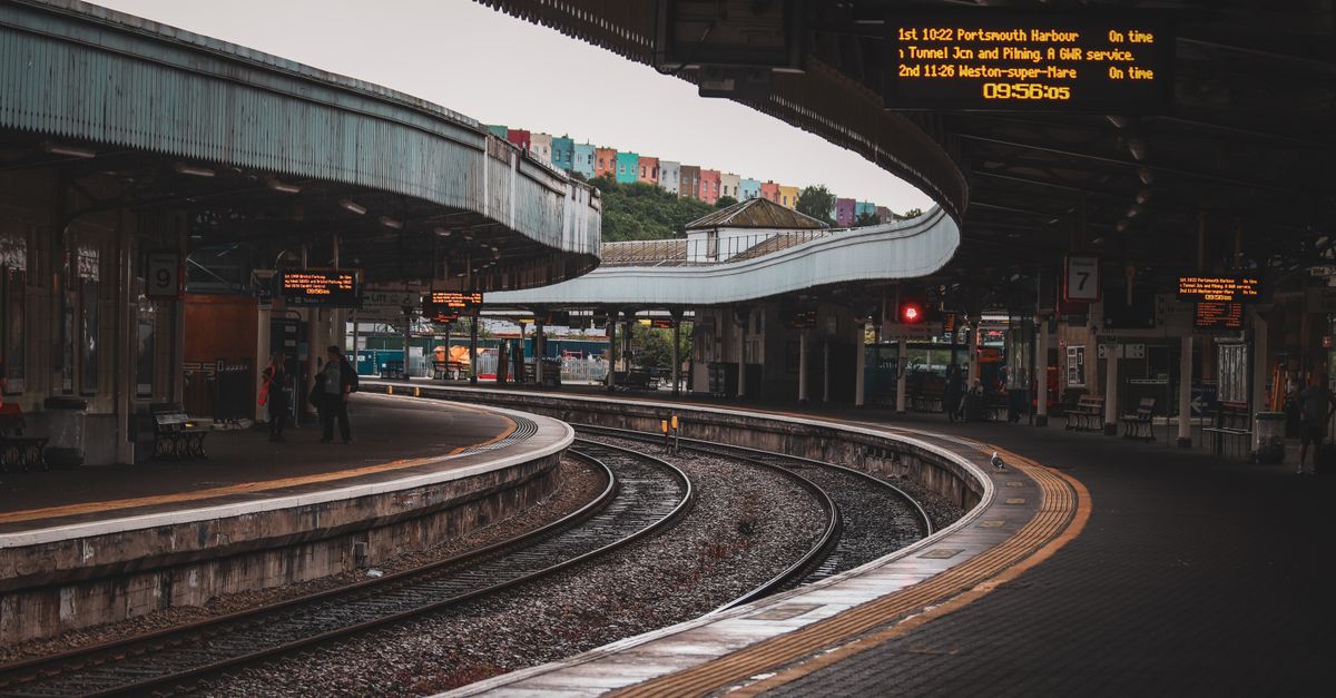 Bristol Temple Meads' curved platforms, with a GWR departure board and the colourful Totterdown hillside houses visible behind.