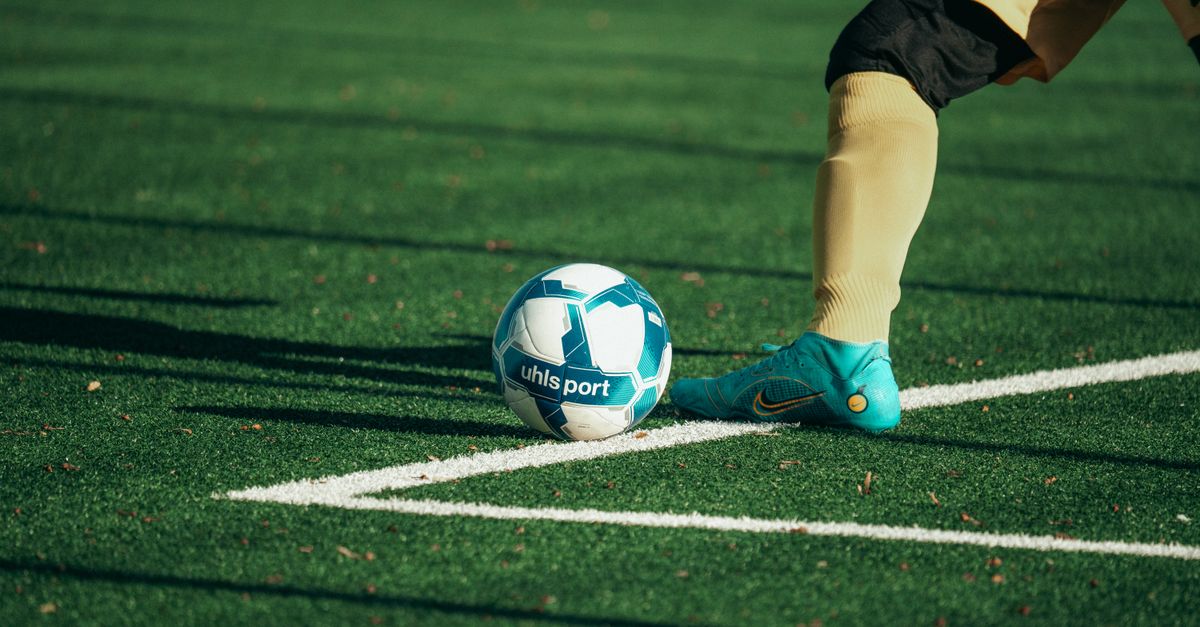 A football boot about to strike the ball on an astroturf pitch